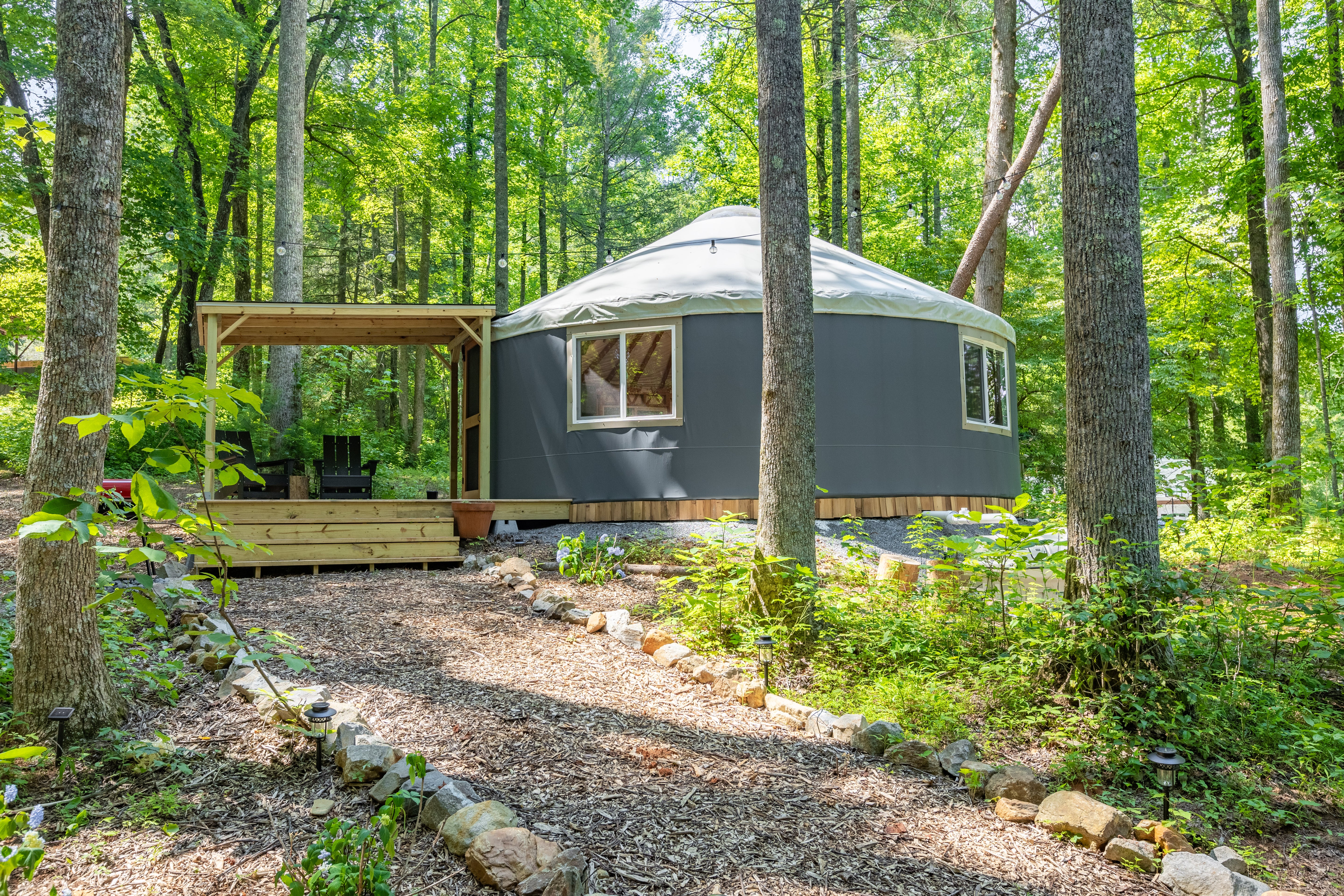 A large circular yurt at Bereishis The Farm, an organic farm in Ellijay, GA, offering farm stays, tours, and photoshoot opportunities. The yurt is surrounded by lush greenery, providing a unique eco-friendly retreat.