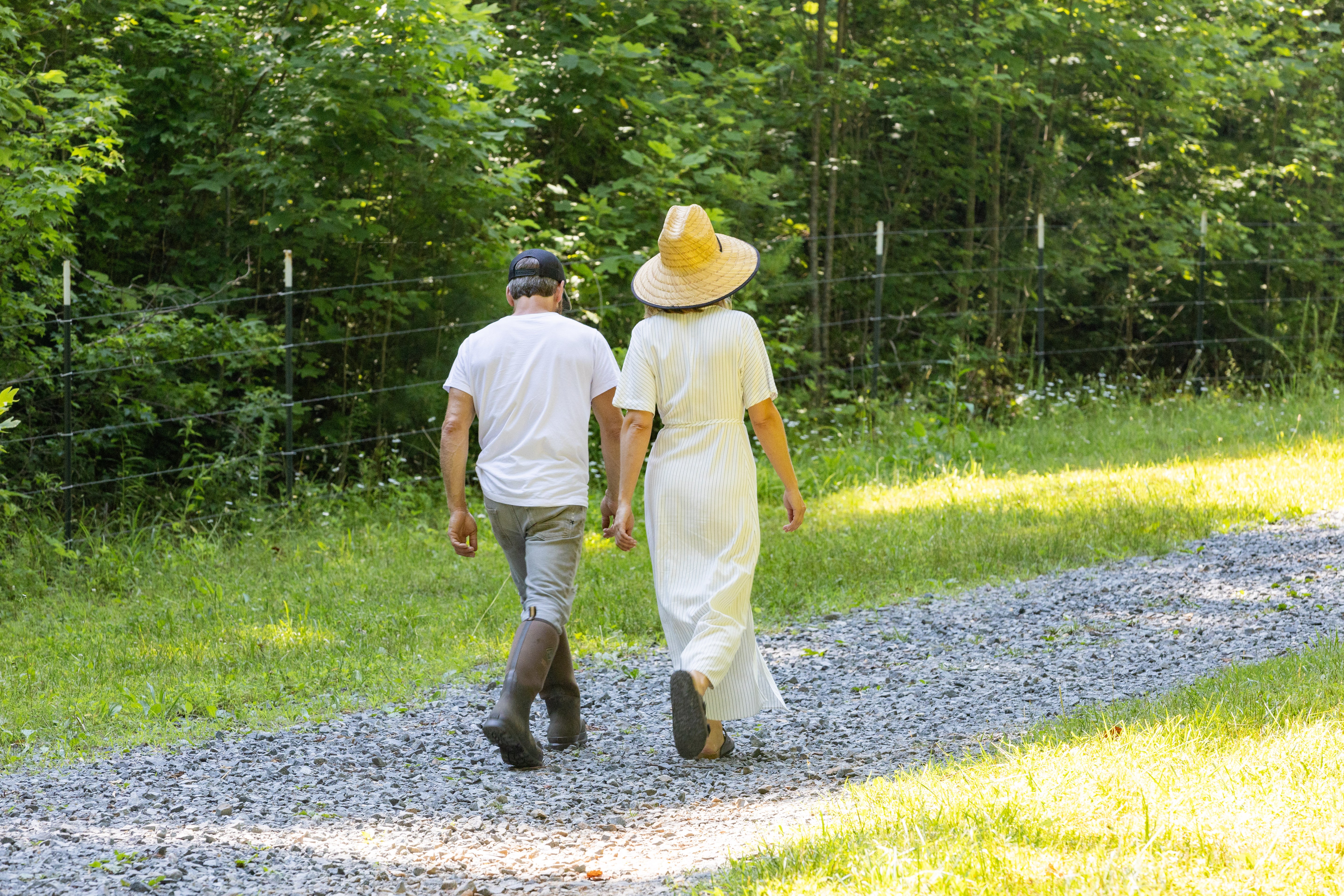 Farmer couple walking along a scenic path on their farm in Ellijay, Georgia, with a yurt stay booking option. Guests can also enjoy animal visits and guided tours at 10675 Chatsworth Hwy, Ellijay, GA 30540.